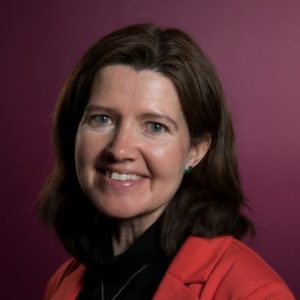 Portrettbilde av Siv Holthe Krogh, seniorrådgiver i Kirkens Nødhjelp. Hun har på sort genser med rød jakke over. 