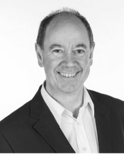 Portrettbilde av Knut Nordenhaug. Han har på seg sort jakke med hvit skjorte under. Bildet er i sort/hvitt. 