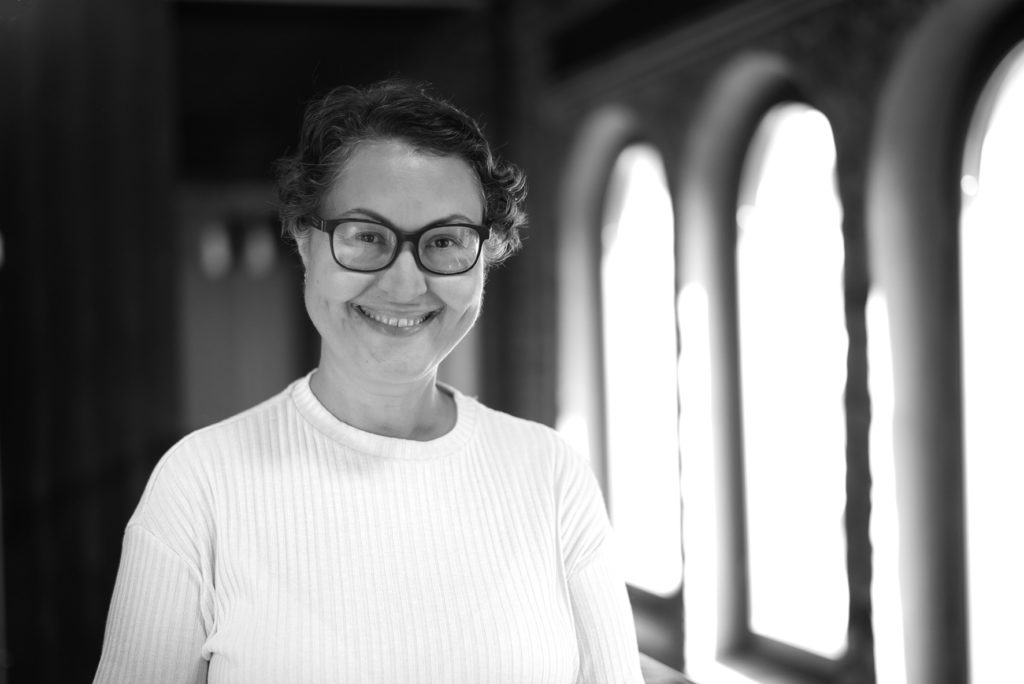 Portrettbilde av Frøydis Johannessen, politisk rådgiver i Fundraising Norge. Hun har mørkt kort hår, mørke briller og på seg en hvit overdel. Hun står foran et vindu.