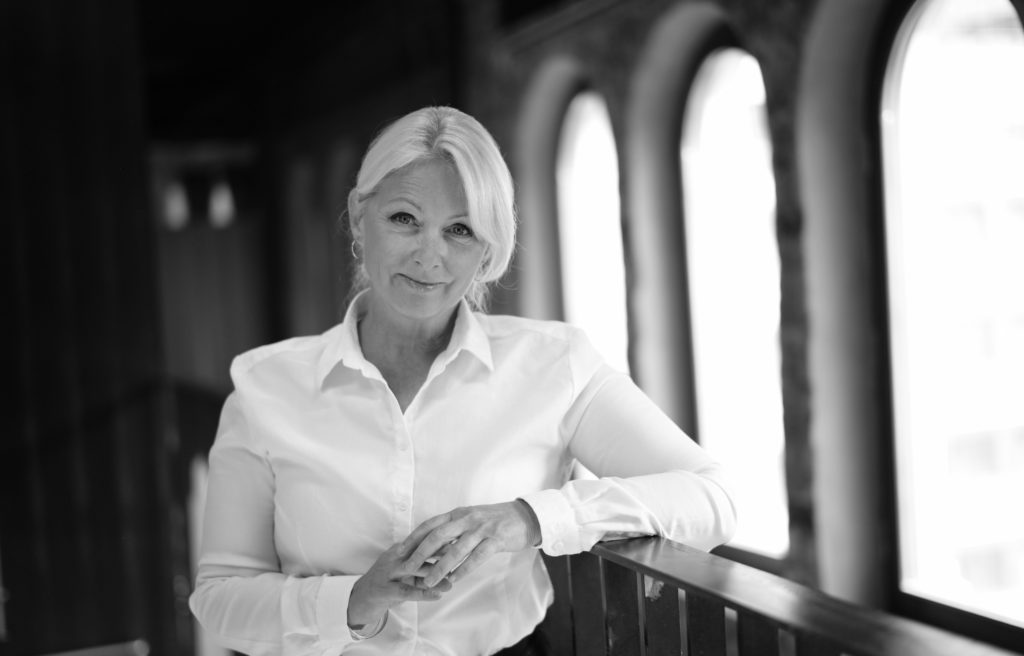 Siri Nodland, generalsekretær i Fundraising Norge. Hun har på seg hvit skjorte, og står mot et gelender inne på Sentralen i Oslo. 