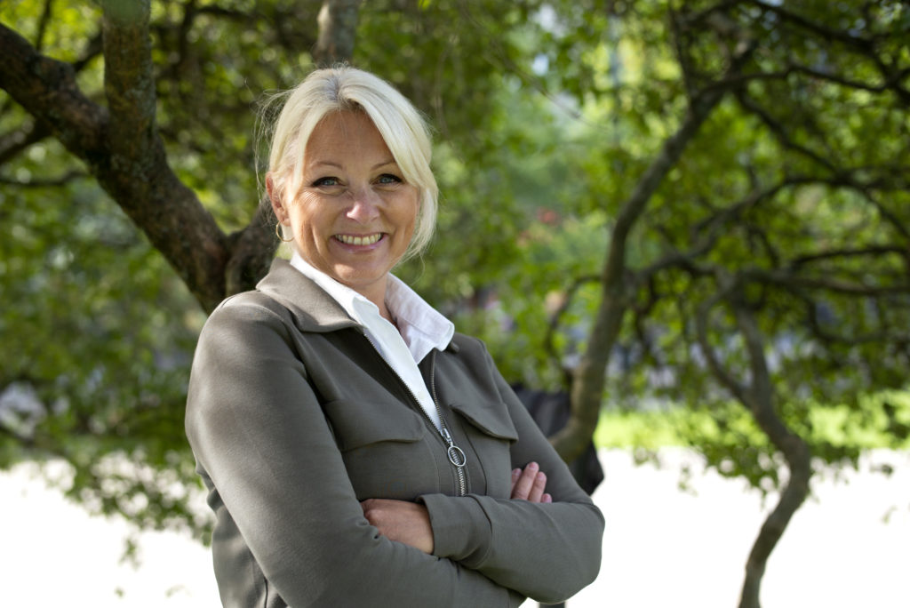 Siri Nodland, generalsekretær i Fundraising Norge. Hun har på seg en hvit skjorte og grønn jakke. Siri står under et tre utenfor Stortinget. 