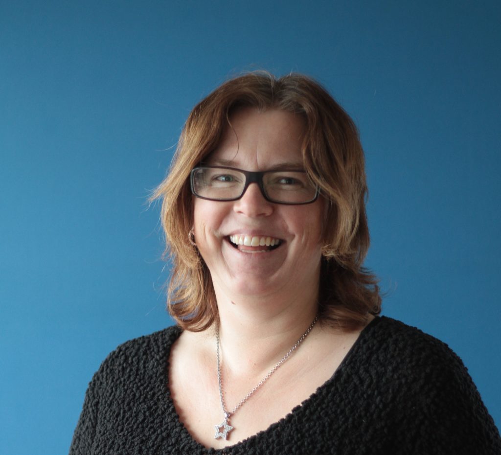 Portrettbilde av Anne Johanne Solhjell, produktansvarlig i Winorg. Hun har på seg sort genser, briller og et sølvsmykke. 