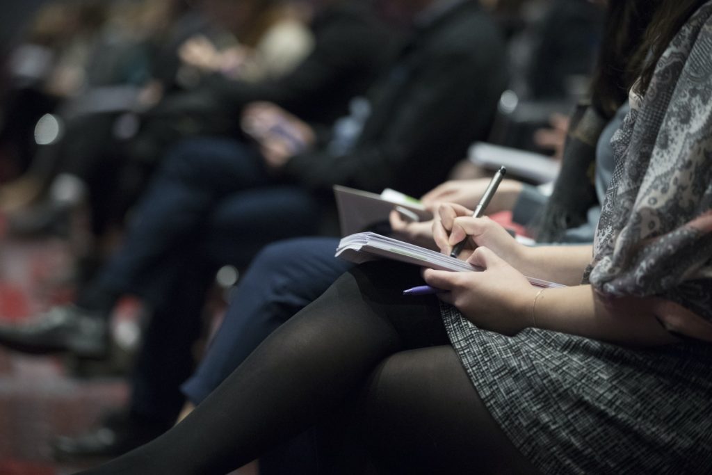 Bilde viser mange mennesker som sitter i en sal på kurs og noterer.