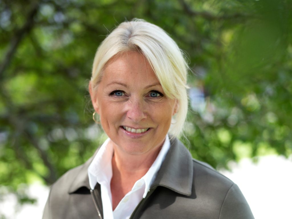 Portrettbilde av Siri Nodland. Hun har på seg hvit skjorte og grønn jakke. 