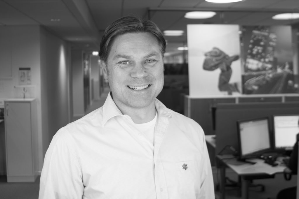 Portrett av Øystein Tamburstuen, spesialrådgiver i Kreftforeningen. Han har på seg hvit skjorte og en pin med Kreftforeningen sin logo.