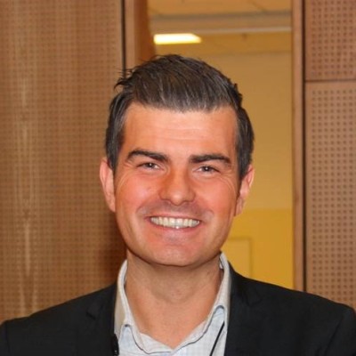 Portrettbilde av Stian Grøstad, sponsorsjef i Gjensidige. Han har på seg lys, rutete skjorte og mørk jakke. 
