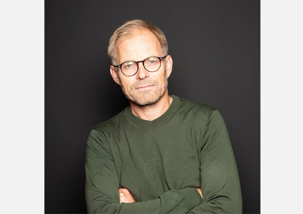 Jon Fredø, byråleder i MVH AS. Han har på seg grønn genser og står foran en mørk bakgrunn. 