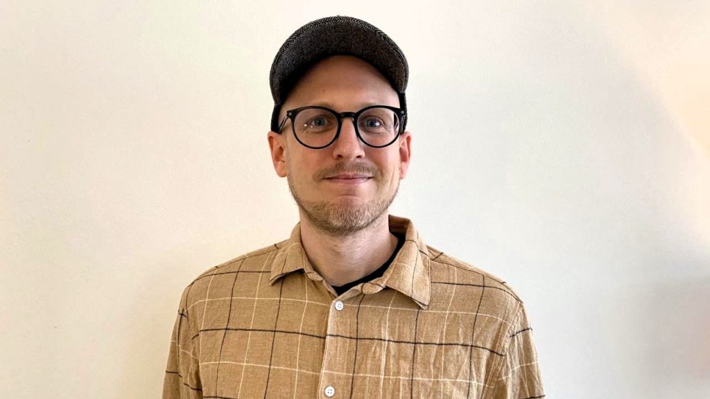 Christian Øygarden, digital rådgiver i Care Norge. Han har på seg beige skjorte med ruter, mørk caps og mørke briller. 