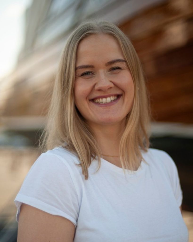 Hanne Buller i Sykehusklovnene. Hun har på seg en hvit t-skjorte og står ute i bybildet. 